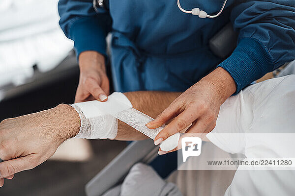 Doctor bandaging a patient s arm during a medical consultation in a clinic