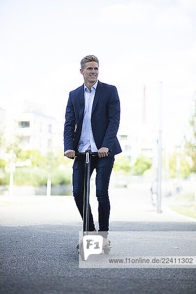 Young businessman riding e-scooter in the city