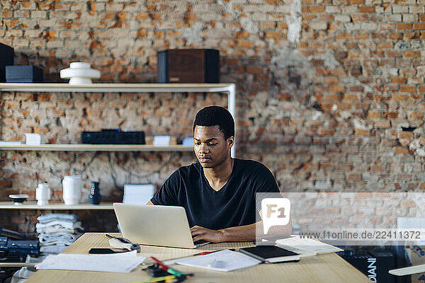 Young man sitting at table using laptop
