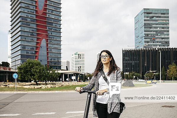 Young businesswoman with e-scooter in the city