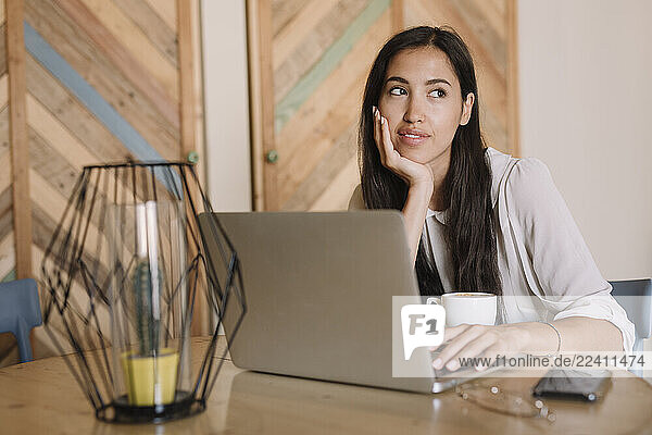 Young businesswoman with laptop at table in a cafe having a break