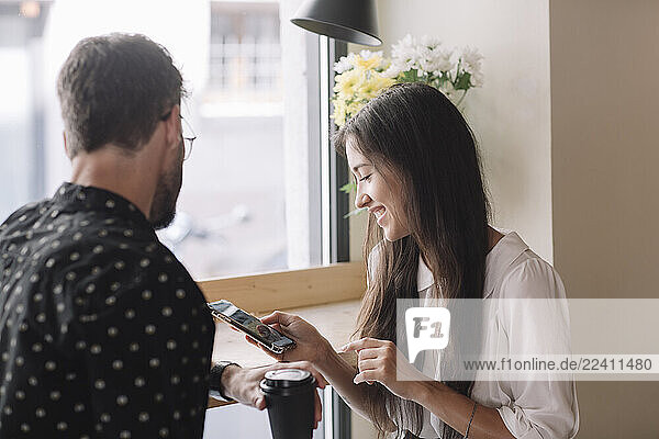 Young couple with disposable cup and smartphone in a cafe