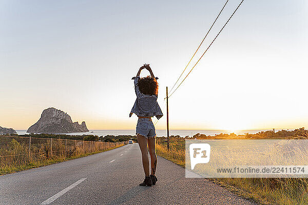Young woman standing on street with raised arms at sunset  Ibiza