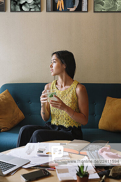 Fashion designer sitting on couch having a break and drinking tea