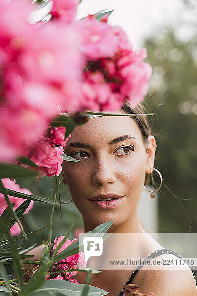 Portrait of young woman in a park with pink blossoming flowers