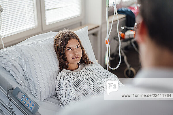 Doctor consulting patient in hospital bed during medical examination