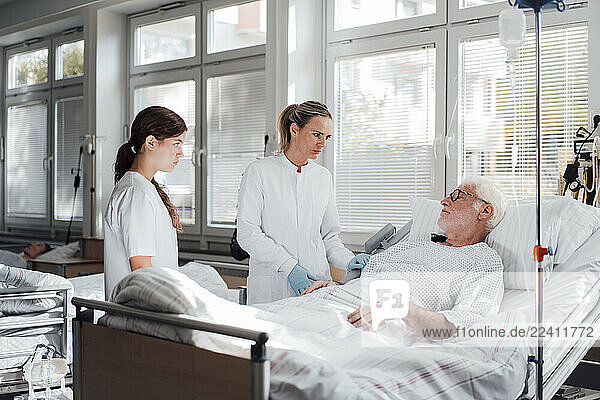 Doctor and nurse consulting with a patient in a hospital room