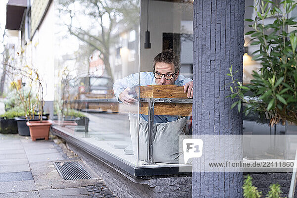 Business man working remotely in a café  appearing thoughtful and hiding behind a table