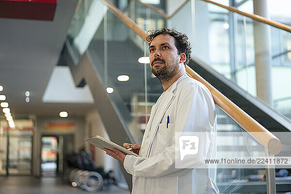 Doctor in a white coat holding a clipboard in a modern clinic