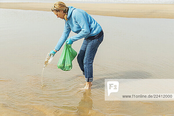 Woman collecting ocean waste during a beach cleanup at the North Sea