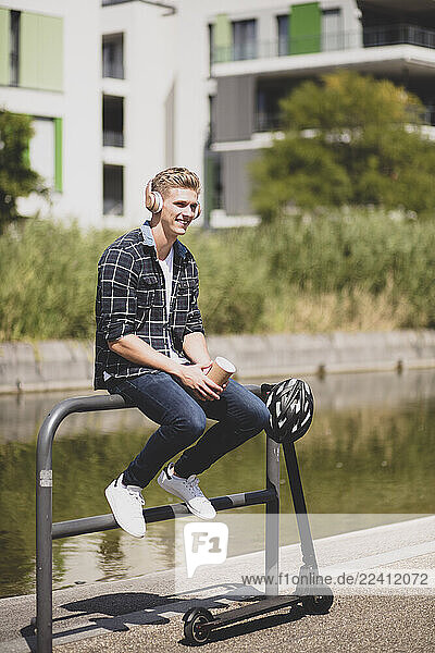 Smiling young man with e-scooter having a break