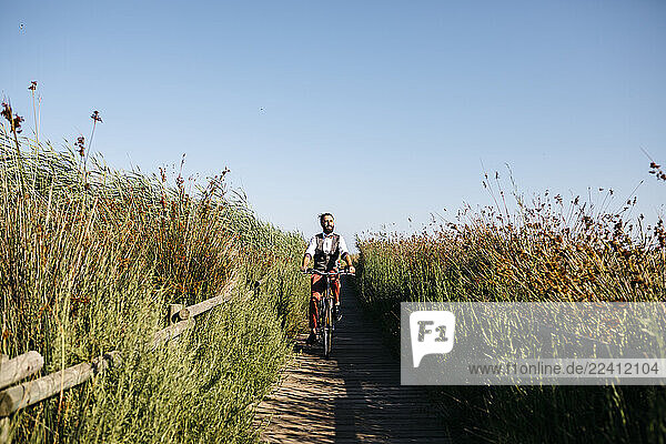 Well dressed man with his bike on a wooden walkway in the countryside after work