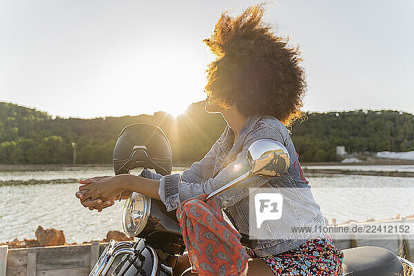 Young woman sitting on motor scooter at sunset  Ibiza