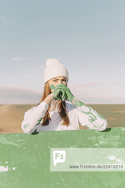 Young woman with green hands  leaning on painting