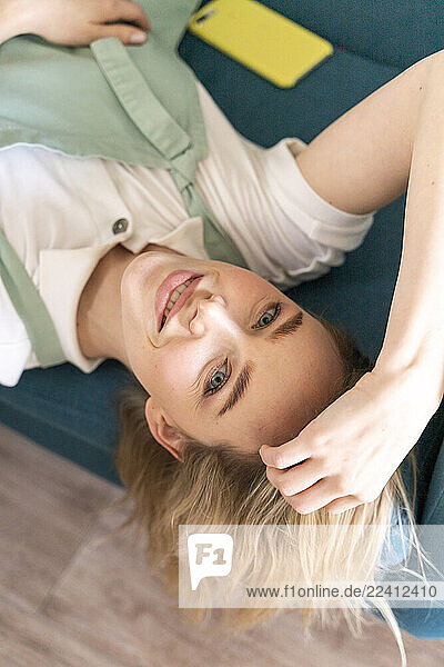Portrait of smiling young woman lying on couch