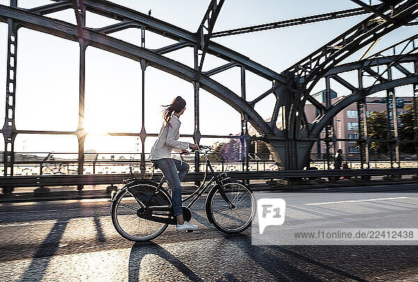 Young cyclist on a bridge at sunset