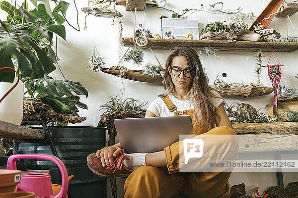 Young woman using laptop in a small gardening shop