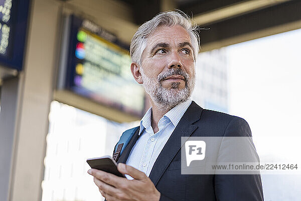 Portrait of mature businessman with cell phone at the station