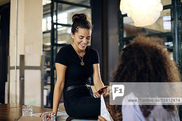 Two happy young businesswomen with smartphone in loft office