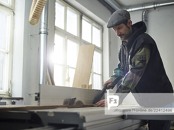 Carpenter sawing wood with circular saw