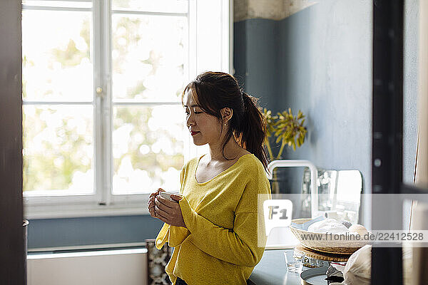 woman drinking tea in office kitchenet
