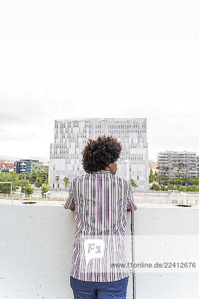 Rear view of young hipster on viewpoint looking to the modern building  Barcelona  Spain