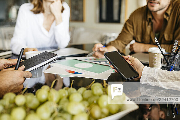 Close-up of coworkers working together on table
