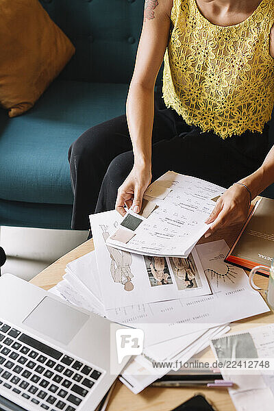 Fashion designer sitting on couch working on a new collection