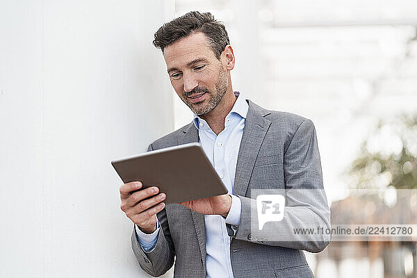 Self-confident businessman in a suit using a tablet indoors
