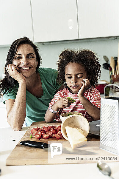 Portrait of happy mother and daughter cooking in kitchen together