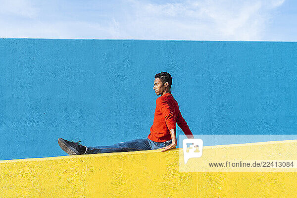 Young dancer stretching on yellow wall