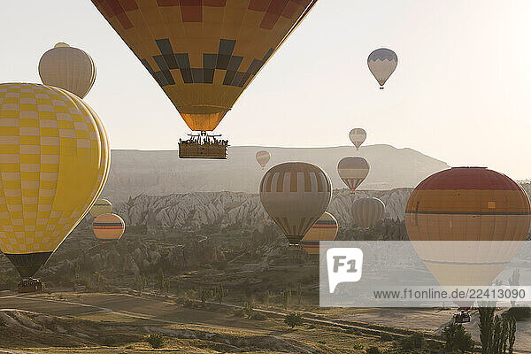 Multi colored hot air balloons flying over mountains at Goreme National Park during sunset  Cappadocia  Turkey
