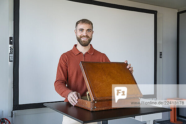 Young man smiling in a modern office with an open leather box