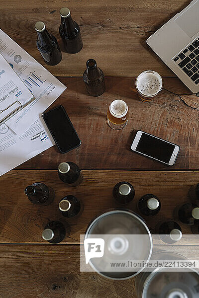 Beer bottles  glasses  documents  smartphones and laptop on table
