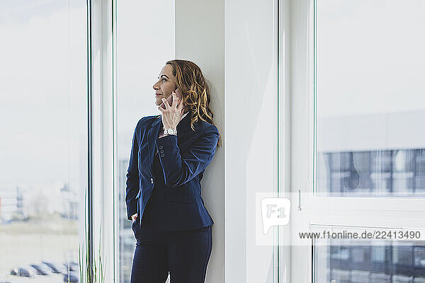 Mature businesswoman on the phone at the window in office