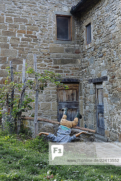 Playful boy doing a headstand at a rustic farmhouse
