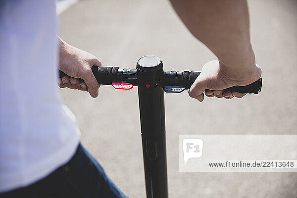 Close-up of hands on handlebar of an e-scooter