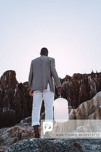 Young man holding empty can looking for water in barren land