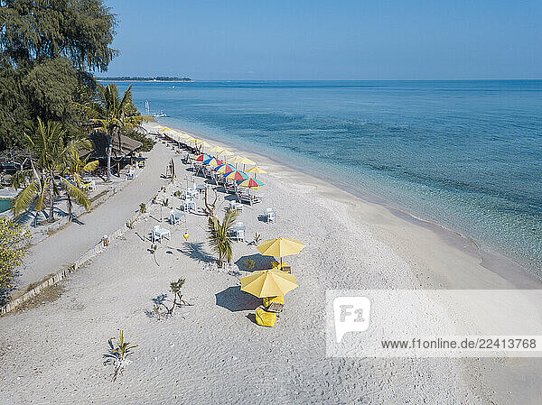 Drone view of chairs and colorful umbrellas arranged at Gili-Air Island against clear blue sky  Bali  Indonesia
