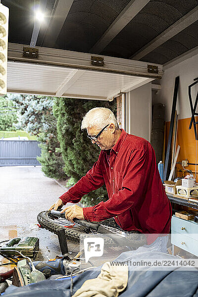 Senior man repairing bicycle tire in garage