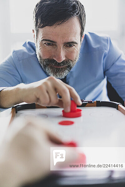 Businessman playing air hockey in office