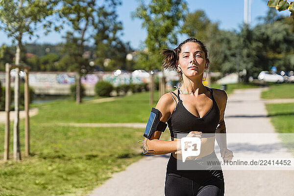 Portrait of young woman running in a park
