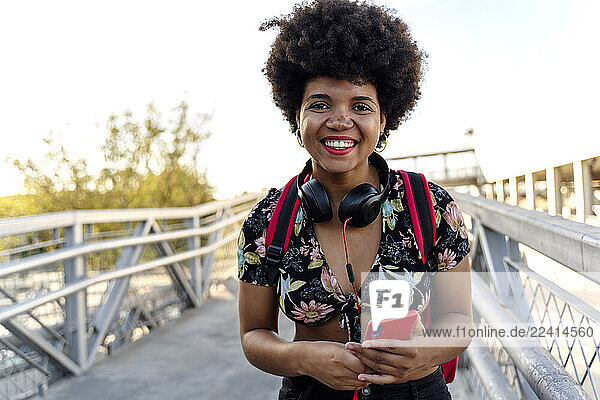 Smiling Afro-American woman with headphones and smartphone