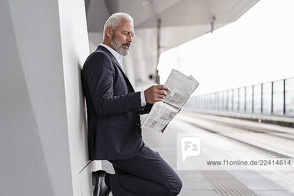 Mature businessman reading newspaper at the station platform