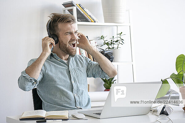 Excited man listening to music at desk in office