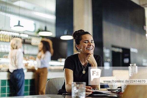 Young woman sitting in bistro  laughing