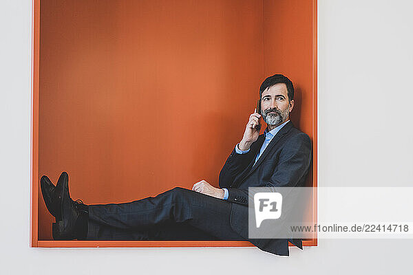 Mature businessman sitting in a niche talking on cell phone