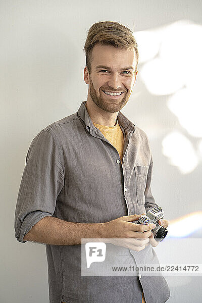 Portrait of smiling man holding old-fashioned camera