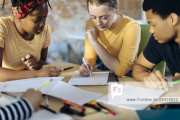 Young people sitting together at table and taking notes
