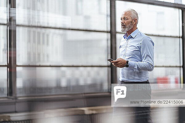Mature businessman with cell phone at the station platform